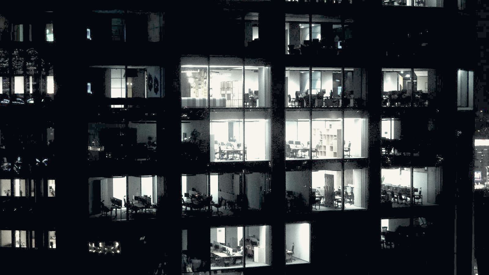 Lit office windows across the facade of an office tower at night