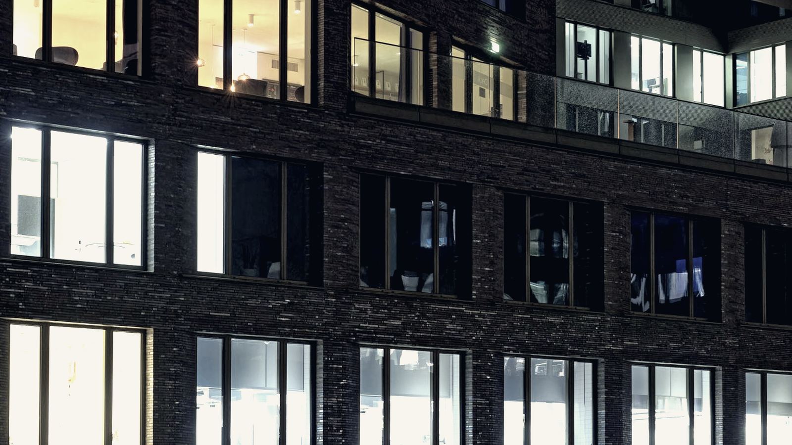 Warmly lit office windows in a brick building in the evening