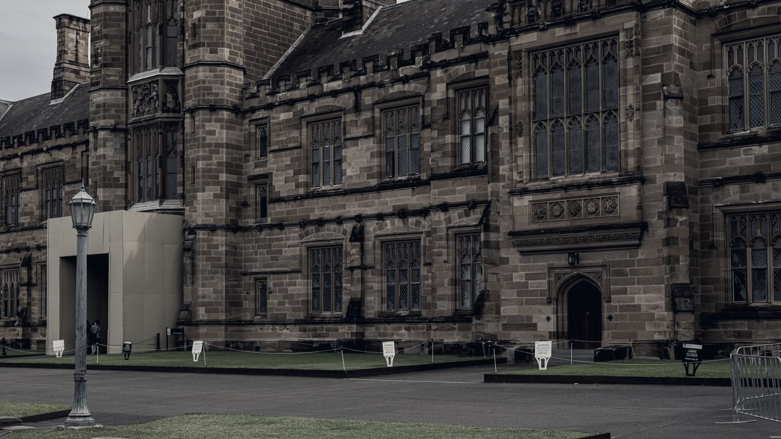 Historic stone university building facing an open campus lawn