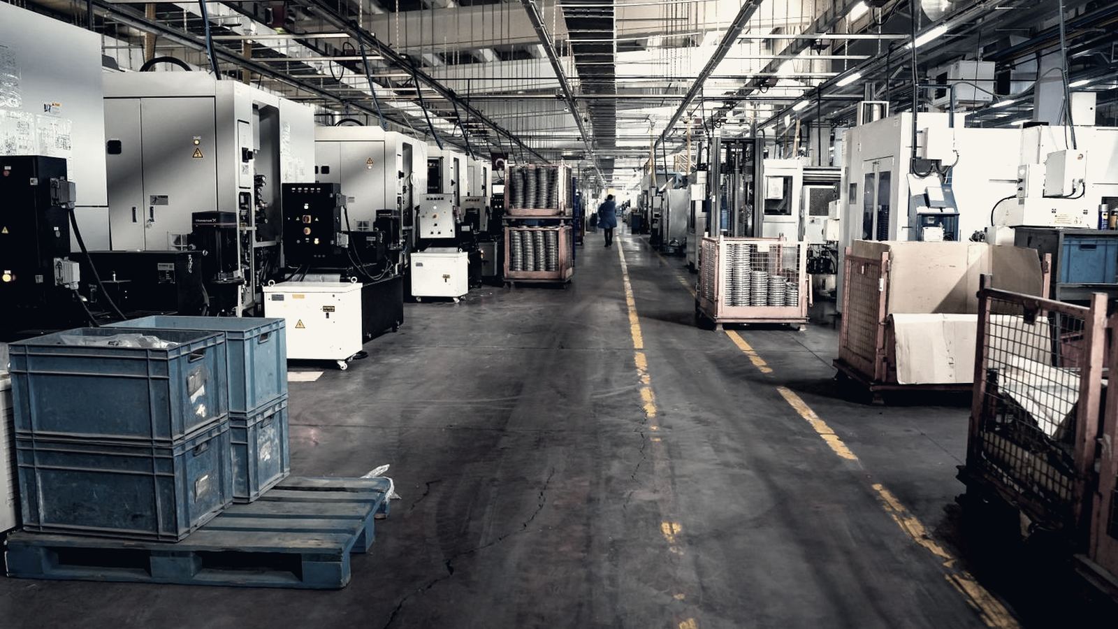 Wide aisle through an industrial factory floor lined with production machinery